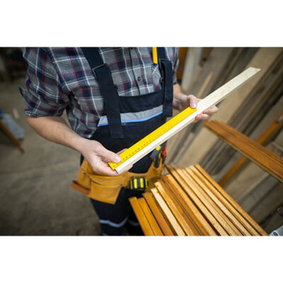 تصویر با کیفیت مرد نجار در حال اندازه گیری چوب با متر