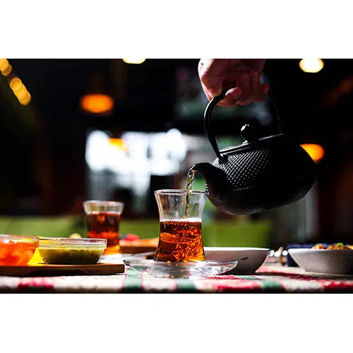 man pouring tea into armudu glass from stone teapot 1 مجموعه