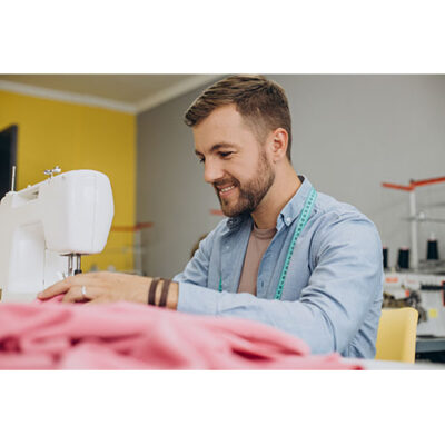 عکس با کیفیت مرد خیاط در حال کار با چرخ خیاطی