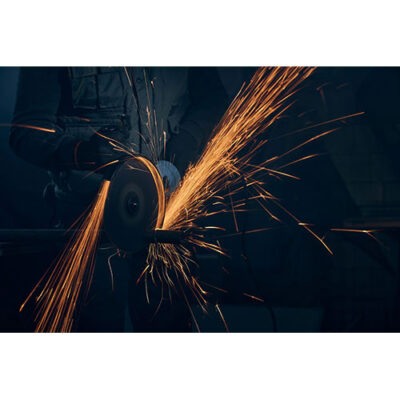 تصویر کارگر آهنگری در حال برش فولاد با سنگ فرز